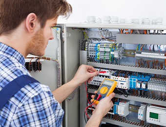Ein Elektriker steht an einem Sicherungskasten